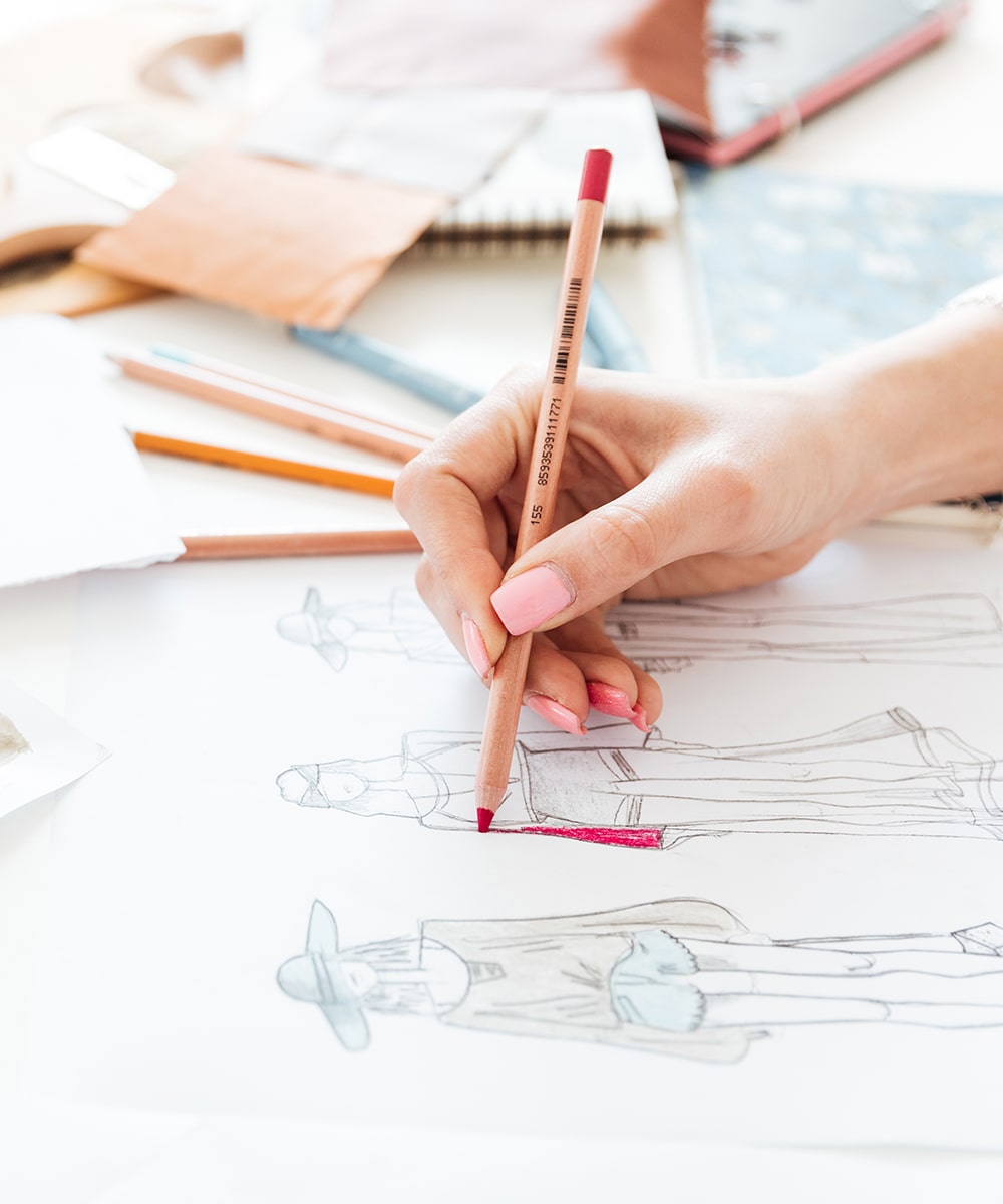 Top view on woman designer drawing clothes sketches